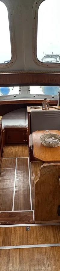 Een interieur van een boot met houten afwerking, een stuurstand, een kombuis en een zithoek. — Cascaruda 920