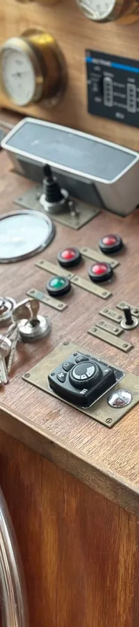 Een houten stuurstand met een houten stuurwiel, diverse meters, schakelaars en een navigatiescherm.