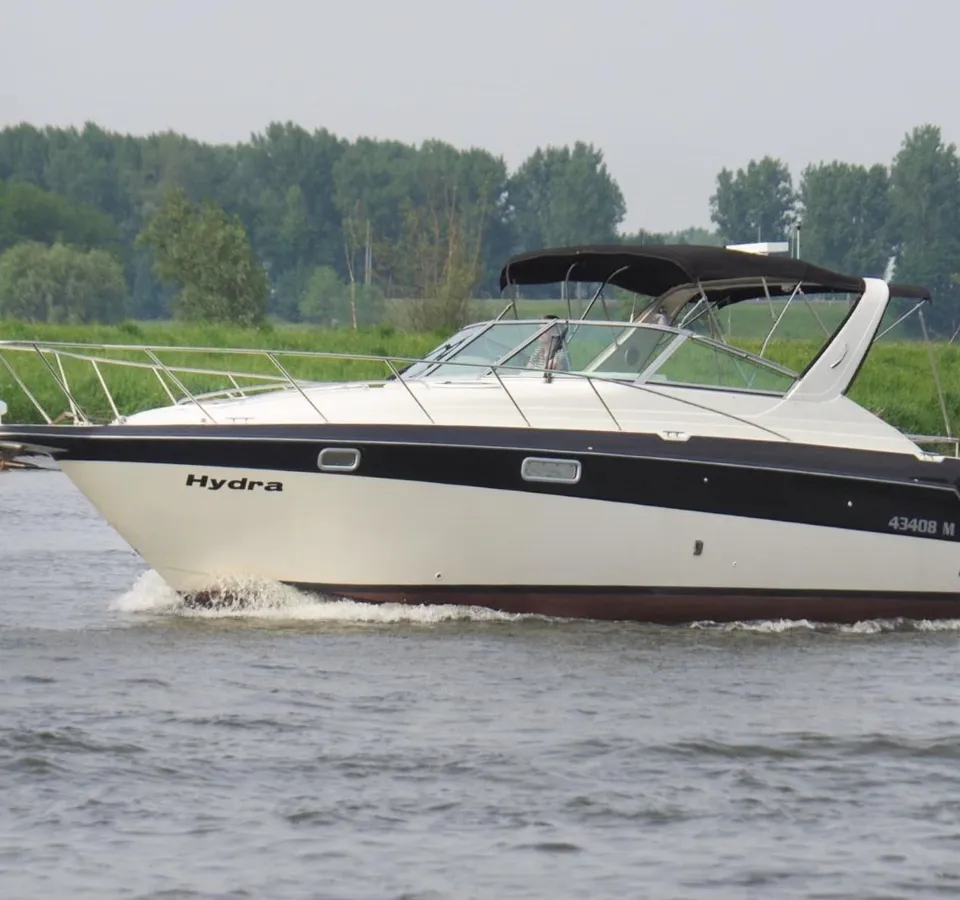 Een witte motorboot met de naam "Hydra" vaart snel over het water, met een grote boeggolf. — Maxum 3200 SCR