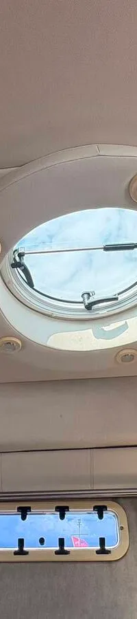 De foto toont het interieur van een boot met een bed, een zithoek met tafel, een keukenblok met spoelbak en kookplaat, en…