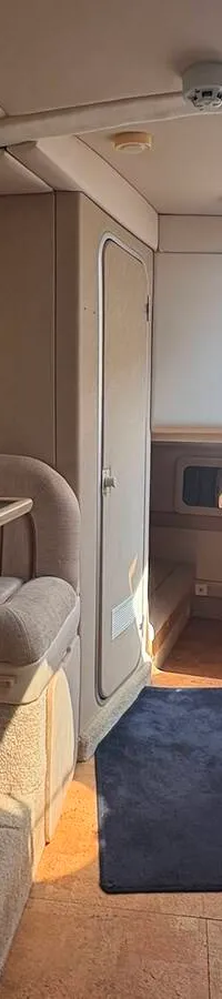 Een witte boot met zwarte accenten en de naam "Hydra" staat op een blauwe trailer voor een gebouw met de tekst…