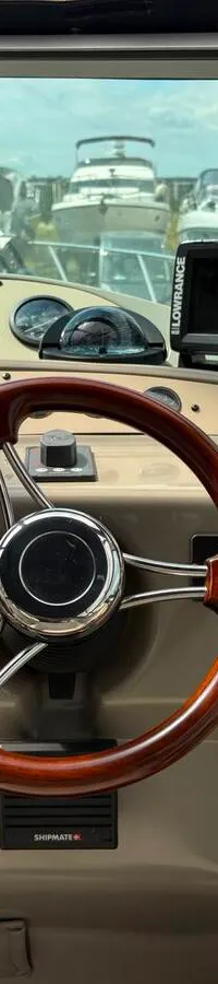 De foto toont het interieur van een boot met een zithoek, tafel, televisie, keukenblok en een doorgang naar buiten.