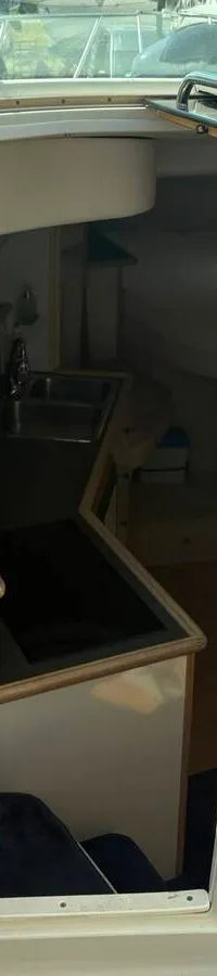 Een interieur van een boot met een keukenblok, inclusief kookplaat, spoelbak, magnetron en koelkast. — Maxum 3200 SCR