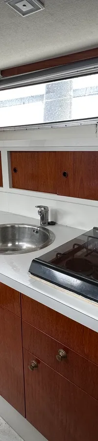 Een kombuis met een aanrecht, spoelbak, kookplaat, magnetron en houten kasten.