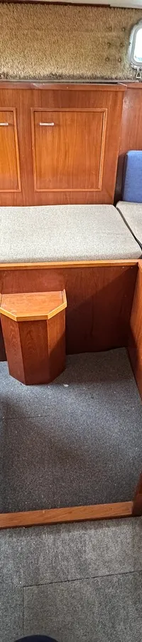 De foto toont een interieur met houten wanden, een bank met kussens, een klein raam en een tapijt op de vloer.