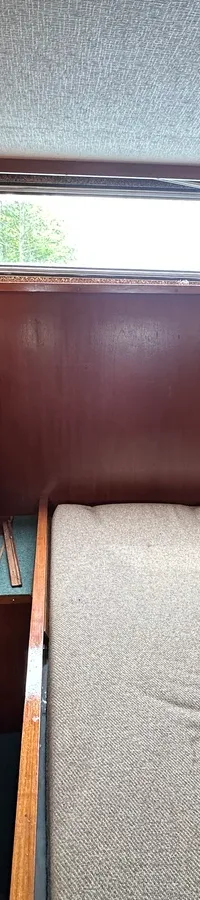 De foto toont een kajuit met een bed, houten wanden, twee ramen en een deur. — Neptunus 107