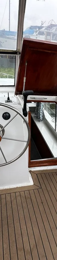 De foto toont het interieur van een boot met een stuurwiel, instrumentenpaneel, een stoel en een houten vloer. — Neptunus 107
