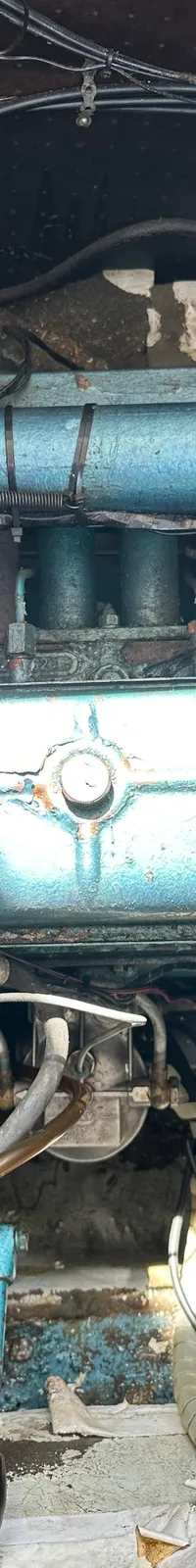 Een close-up van een blauw geverfde scheepsmotor met diverse leidingen, slangen en bedrading.