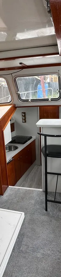 De foto toont het interieur van een boot met een stuurstand, zithoek, bar met krukken en een kombuis. — Neptunus 107