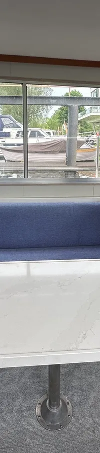 De foto toont het interieur van een boot met een zithoek, een tafel en een stuurstand. — Neptunus 107