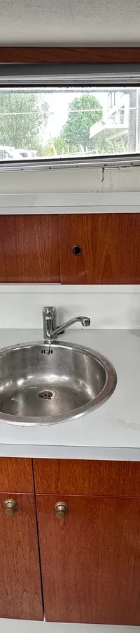 Een kombuis met een magnetron, spoelbak, vierpits gasfornuis, koelkast en houten kasten.