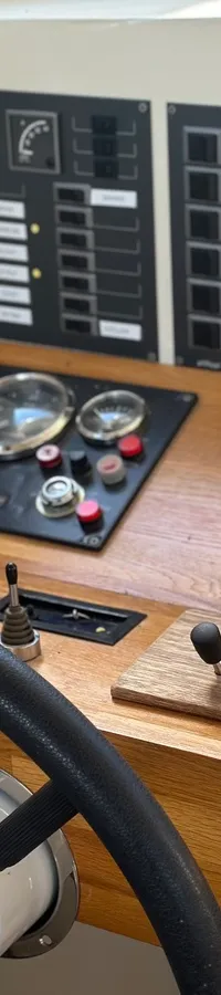 Een stuurwiel met een houten dashboard met diverse meters en schakelaars.