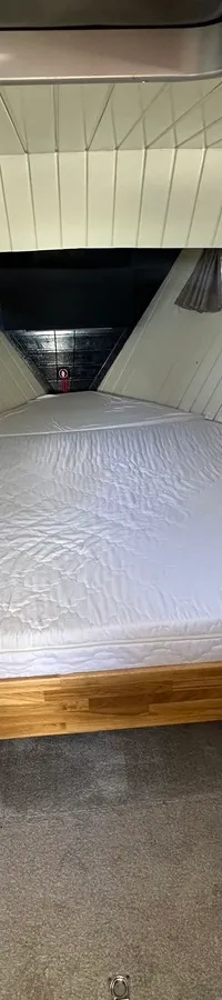 Een kajuit met een groot bed, twee kleine ramen met gordijnen en een brandblusser. — Oomen kruiser fly