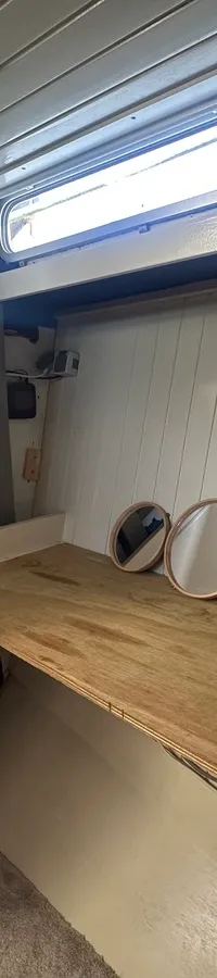 De foto toont het interieur van een boot met een houten werkblad, twee ronde spiegels en een brandblusser.