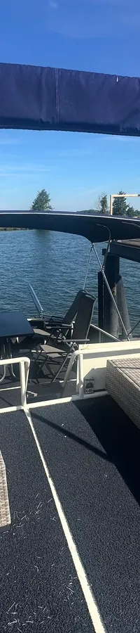 De achterkant van een boot met een donkerblauwe biminitop, twee rieten banken en een tafel met stoelen. — Oomen kruiser fly