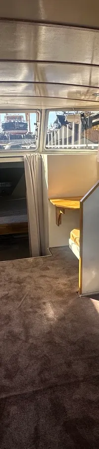 De foto toont het interieur van een boot met een stuurstand, bank, keukenblok en uitzicht naar buiten. — Oomen kruiser fly