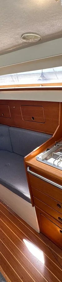 De foto toont het interieur van een boot met een kombuis, zithoek en een doorgang naar een slaapcabine. — Compromis 777