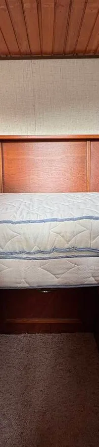 Een kajuit met houten lambrisering, twee matrassen op een bedframe en patrijspoorten. — Smelne 950 ak