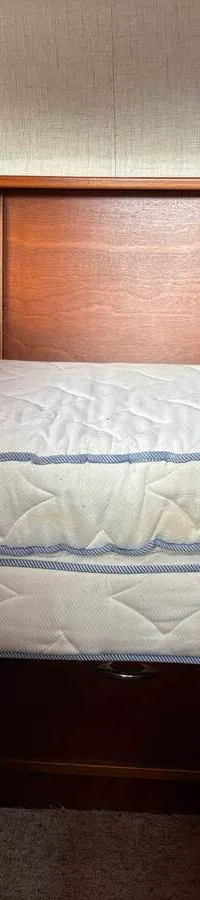 Een kajuit met een wit matras, houten wanden en twee patrijspoorten. — Smelne 950 ak