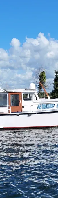 Een witte motorboot met een rode streep op de romp vaart op blauw water onder een bewolkte hemel. — Smelne 950 ak
