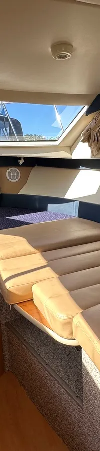 Twee boten liggen aangemeerd, de voorste boot is wit met een blauwe streep en heeft een anker aan de boeg.