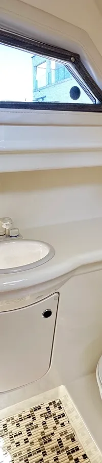 Een blauw-witte boot ligt aangemeerd aan een steiger, met een andere boot erachter en waterlelies op het water.