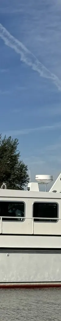 Een witte motorboot met de naam "M.S. Compagnon" ligt in het water, met een rode onderkant en zwarte stootrand.