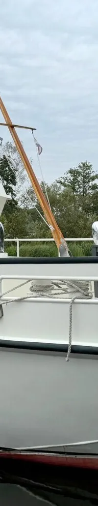 Een witte boot met de naam "M.S. Compagnon" ligt afgemeerd aan een houten steiger.