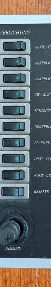 Een zwart bedieningspaneel met witte tekst en diverse schakelaars, knoppen en indicatielampjes.