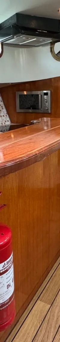 Een interieur van een boot met een houten bar, een tapkraan, een keukenblok en een brandblusser.