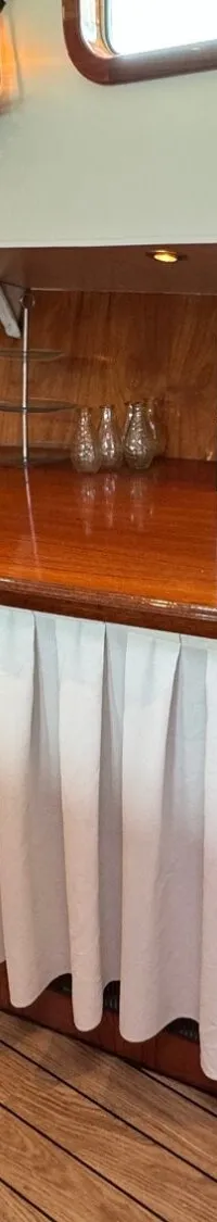Een houten bar met een wit geplooid gordijn eronder, met diverse glazen, borden en dozen erop.