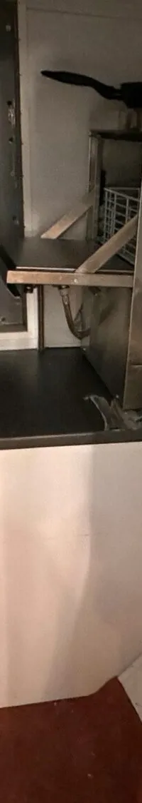 De foto toont een kombuis met een roestvrijstalen spoelbak, kraan, pannen, een brandblusser en een frituurpan.