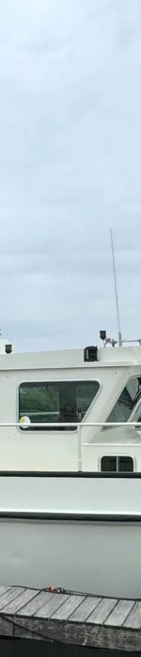 Een witte motorboot met de naam "M.S. Compagnon" ligt afgemeerd aan een houten steiger.
