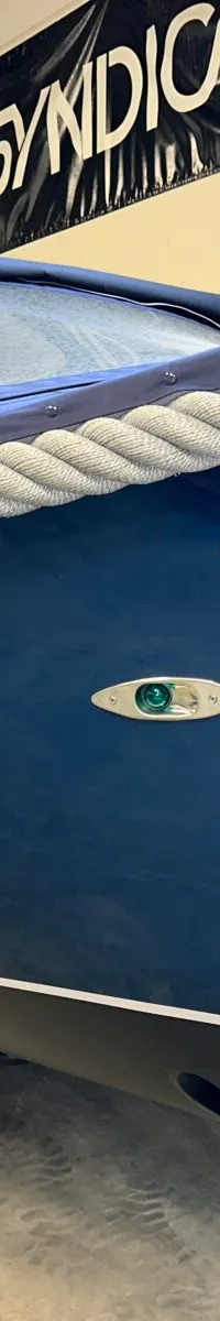 Een donkerblauwe boot met de naam "Dutch Steel" op de zijkant, voorzien van een touwstootrand en een blauwe kap.