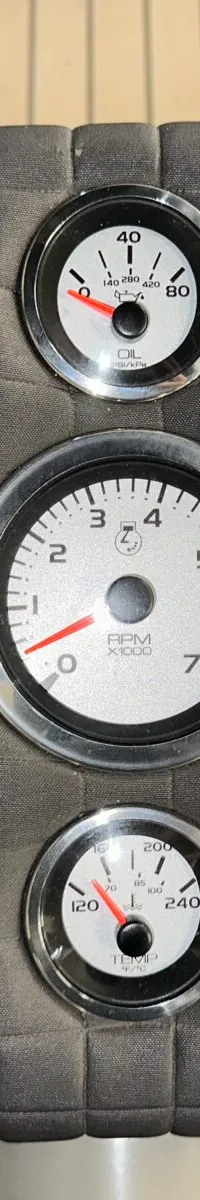 Een detailfoto van een grijs, gestoffeerd bedieningspaneel met drie ronde meters en een Side-Power thruster bediening.