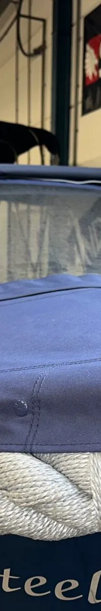 Een blauwe boot met een blauw dekzeil en een dikke grijze touwrand, met de tekst "Dutch Steel" op de zijkant.