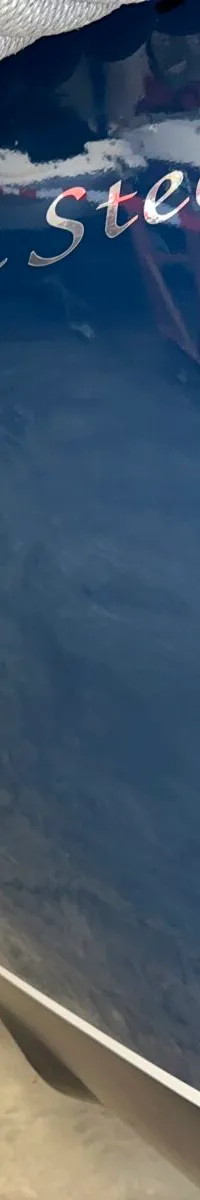 De foto toont de zijkant van een donkerblauwe boot met de naam "Dutch Steel" in zilveren letters.