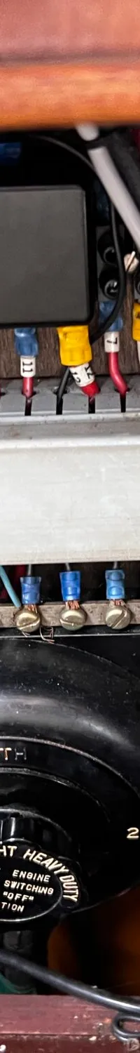 Een detailfoto van een elektrisch paneel met diverse draden, klemmenstroken en een draaischakelaar.