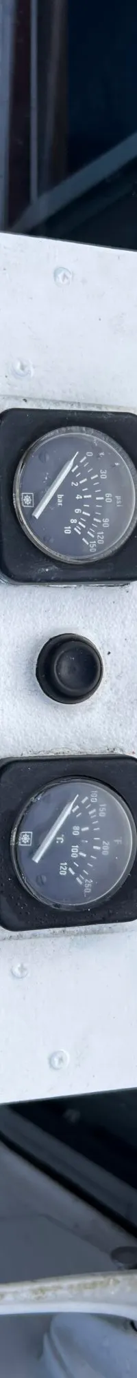 Een wit bedieningspaneel met twee ronde meters, een joystick en een sleutelbos met een label "JOSINA-M".