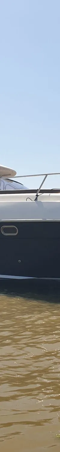 Een donkerblauwe en witte motorboot ligt in bruin water onder een helderblauwe lucht. — Airon Airon Marine 425 HT