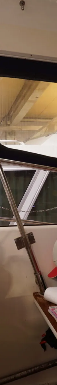 Een interieur van een boot met een stuurwiel, een witte stoel en een tijdschrift op een houten plank.