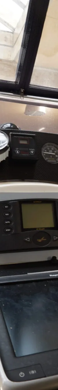 De foto toont een deel van het dashboard van een boot met diverse meters, een navigatiescherm en bedieningselementen.
