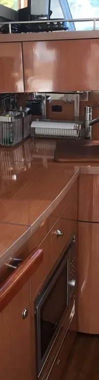 De foto toont een kombuis met houten kasten, een aanrecht, een gootsteen, een kraan en een magnetron.