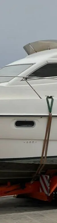 Een witte motorboot met de naam "SEALINE" op de zijkant staat op een oranje trailer, vastgezet met spanbanden.