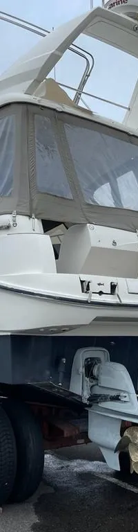 Een witte motorboot met een donkerblauwe romp staat op een trailer met twee motoren aan de achterzijde.