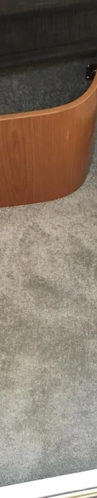 De foto toont een interieur met grijze vloerbedekking, houten panelen en een wit matras.