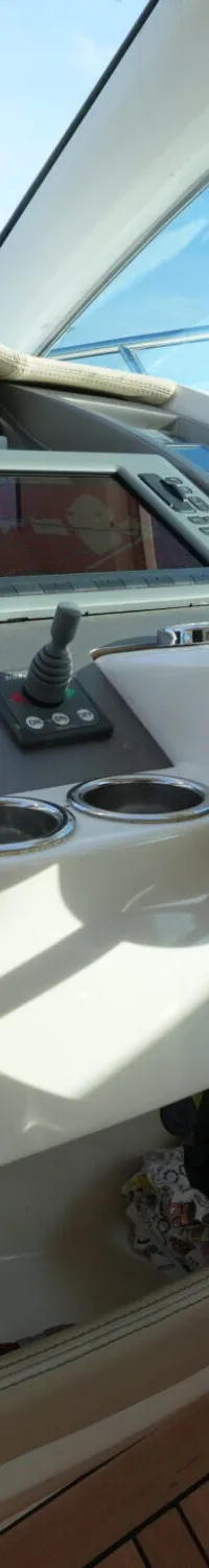 De cockpit van een boot is zichtbaar, met een stuurwiel, navigatiescherm, diverse meters, een joystick en een Sony-radio.