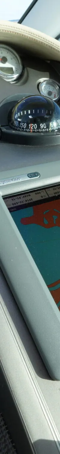 De foto toont een bootdashboard met diverse meters, een kompas, een Raymarine dieptemeter/snelheidsmeter en een kaartplotter.