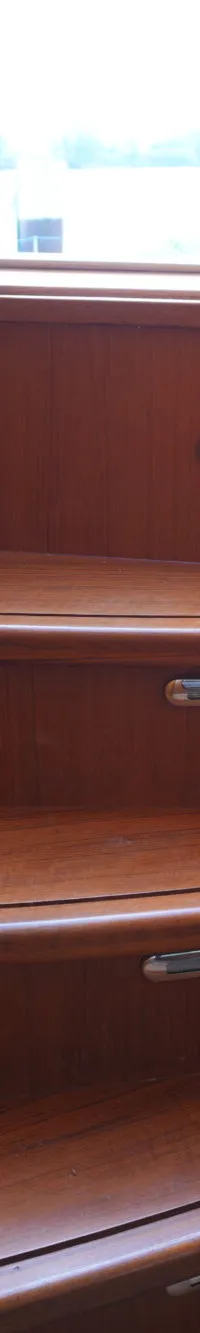 Een houten trap met drie treden en ingebouwde verlichting, naast een raam met een blauw gordijn.