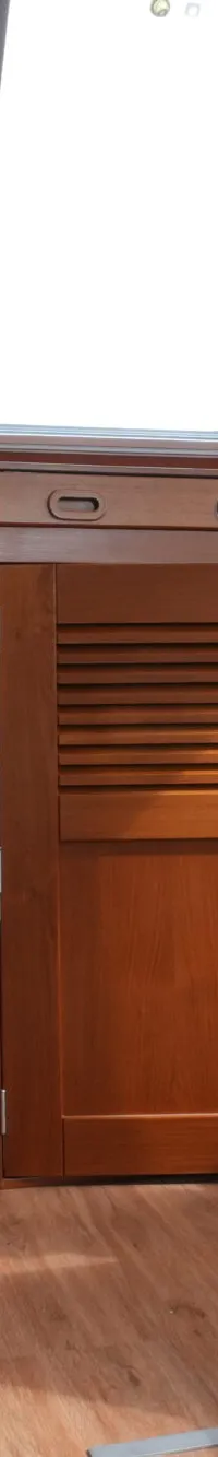 Een interieur van een boot met houten panelen, een stuurconsole met meters en ramen met blauwe gordijnen.